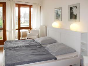 a white bedroom with a bed and a window at Holiday Home Strandvilla - LUB117 by Interhome in Lubmin