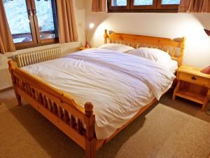 1 dormitorio con cama de madera con sábanas blancas en Apartment Arsets 203-12 by Interhome, en Arveyes