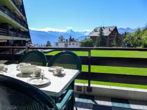 a table and chairs on a balcony with a view at Apartment Victoria A-B-C-2 by Interhome in Crans-Montana