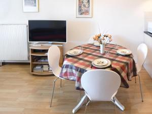 a dining room table with white chairs and a television at Apartment Victoria B 7 by Interhome in Crans-Montana