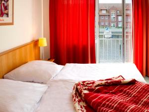 ウッカーミュンデにあるApartment Lagunenstadt Ueckermünde-5 by Interhomeのベッドルーム1室(赤いカーテンと窓付きのベッド1台付)