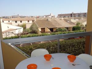einen weißen Tisch und Stühle auf einem Balkon mit Aussicht in der Unterkunft Apartment Voiles d'Or-Gênois-1 by Interhome in Le Grau-du-Roi