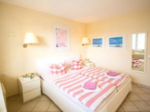 ツィノヴィッツにあるApartment Zur Düne II by Interhomeのベッドルーム1室(ピンクと白のストライプの大型ベッド1台付)