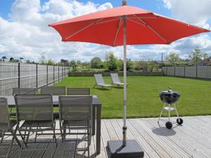 a red umbrella on a deck with chairs and a grill at Holiday Home La Goulvinoise by Interhome in Goulven