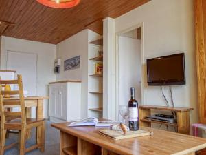 a room with a table with a bottle of wine and a television at Apartment Le 2100 A et B - Lavachet-9 by Interhome in Tignes
