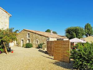 a stone house with a wooden fence in front of it at Holiday Home Tuilières by Interhome in Cissac-Médoc
