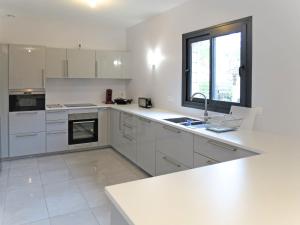 a kitchen with white cabinets and a sink and a window at Holiday Home Yara - LCA126 by Interhome in Lacanau