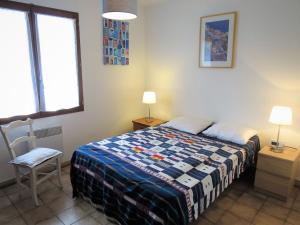 a bedroom with a bed and a chair and a window at Holiday Home Caberal by Interhome in Soulac-sur-Mer