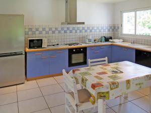 メサンジュにあるHoliday Home Le Moïsan - MES120 by Interhomeのキッチン(青いキャビネット、テーブル、電子レンジ付)