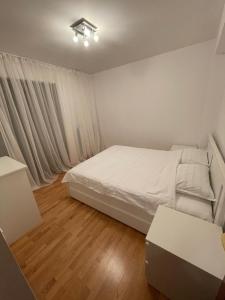 1 dormitorio con cama blanca y suelo de madera en Mikerynos 1 en Sinaia