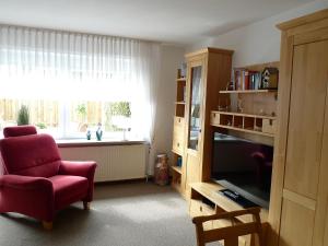 uma sala de estar com uma cadeira vermelha e uma televisão em Apartment Dehne-1 by Interhome em Norddeich