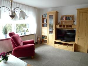 uma sala de estar com uma cadeira vermelha e uma televisão em Apartment Dehne-1 by Interhome em Norddeich
