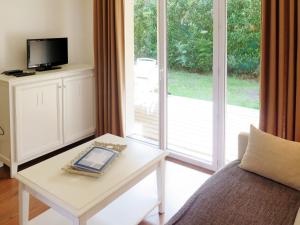 ein Wohnzimmer mit einem Tisch, einem TV und einem Sofa in der Unterkunft Apartment Les Cottages du Lac T1 by Interhome in Parentis-en-Born