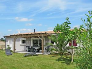 a white house with a patio and a yard at Holiday Home Dorgeles - SUL130 by Interhome in Soulac-sur-Mer