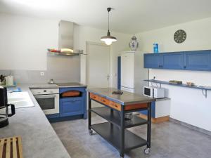a kitchen with blue cabinets and a table in it at Holiday Home Dorgeles - SUL130 by Interhome in Soulac-sur-Mer