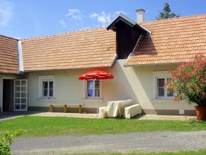 ein Haus mit zwei Stühlen und einem roten Regenschirm in der Unterkunft Holiday Home Friedl by Interhome in Ritzing
