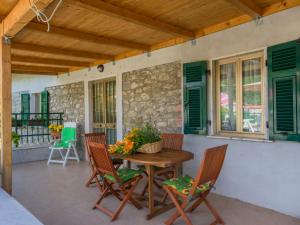 un patio con mesa, sillas y pared de piedra. en Holiday Home Il Frantoio by Interhome, en Codiponte