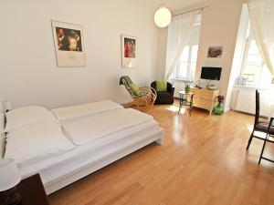 a bedroom with a white bed and a living room at Apartment Am Margaretenplatz by Interhome in Vienna