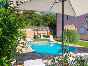 - une piscine avec des chaises et un parasol dans la cour dans l'établissement Apartment Chantal - RAC151 by Interhome, à Rabac