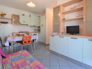 eine Küche mit weißen Schränken und einem Tisch mit einem TV in der Unterkunft Apartment Solmare-7 by Interhome in Rosapineta