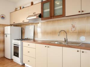 a kitchen with white cabinets and a sink and a refrigerator at Apartment Matius - RAB105 by Interhome in Rab