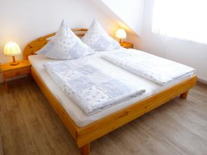 ノルトダイヒにあるApartment Ballertutje by Interhomeのベッドルーム1室(白いシーツと枕が備わる木製ベッド1台付)