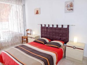 a bedroom with a bed with a red and orange blanket at Apartment Le Nirvana-1 by Interhome in Le Grau-du-Roi