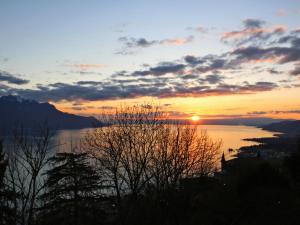 a sunset over a body of water with the sun setting at Apartment View Riviera by Interhome in Glion