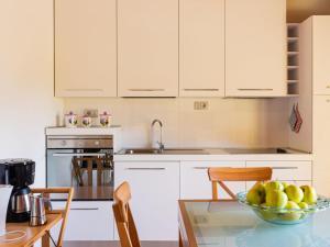 una cucina con armadi bianchi e un cesto di frutta sul tavolo di Apartment Giuse - DMA205 by Interhome a Domaso