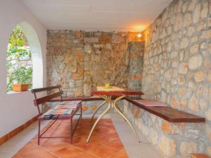 una camera con un muro in pietra, tavolo e panche di Apartment Donata by Interhome a Senj