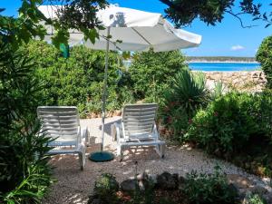 two chairs under an umbrella on the beach at Apartment Noa - RAB112 by Interhome in Rab