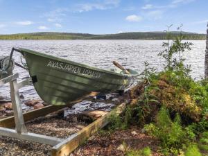um barco verde sentado na margem de um lago em Holiday Home Äkäsjärven lomamökit 3 by Interhome em Rauhala