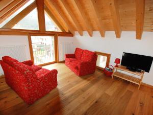 sala de estar con 2 sillas rojas y TV de pantalla plana en Apartment Albergo Diffuso - Cjasa de Barce-2 by Interhome, en Barcis