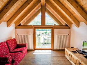 sala de estar con sofá rojo y ventana en Apartment Albergo Diffuso - Cjasa de Barce-2 by Interhome, en Barcis