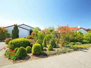 un jardín con arbustos y flores frente a una casa en Holiday Home Noordzeepark Zeewind by Interhome en Mispelburg