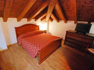 a bedroom with a bed and a dresser with a television at Apartment Albergo Diffuso - Cjasa Fantin by Interhome in Barcis