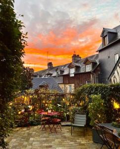 a patio with a table and chairs at sunset at La Cour Sainte Catherine demeure de charme in Honfleur