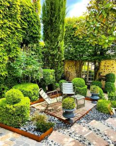 a garden with two chairs and trees and bushes at La Cour Sainte Catherine demeure de charme in Honfleur