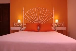 um quarto com uma cama grande e uma parede laranja em Hotel Playa de las Catedrales em Reinante