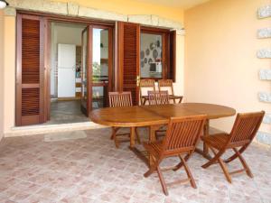 a dining room with a wooden table and chairs at Apartment Borgo Le Logge - pool - BUD117 by Interhome in Budoni