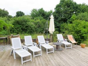a group of four chairs and an umbrella on a deck at Holiday Home Aucéloun - NAS100 by Interhome in Nassiet