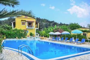 a swimming pool with chairs and umbrellas next to a building at Kapases Studios & Apartments in Peroulades