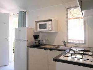 Porto FalconeraにあるHoliday Home Camping Laguna Village-1 by Interhomeの白い冷蔵庫と電子レンジのあるキッチン