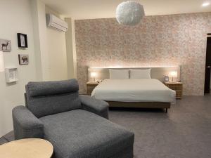 una camera da letto con un letto, un divano e una sedia di Ta 溫泉會館 a Jiaoxi