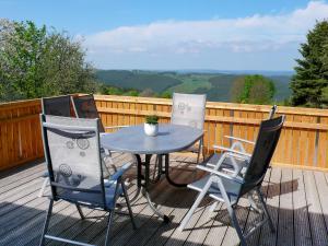 three chairs and a table on a deck at Chalet Weitsicht by Interhome in Lichtenhain