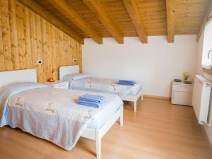 2 letti in una camera con pareti in legno e pavimenti in parquet di Holiday Home Albergo Diffuso - Cjasa Paron Cilli by Interhome a Barcis