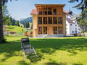 einen Stuhl im Gras vor einem Haus in der Unterkunft Holiday Home von Capeller by Interhome in Parpan