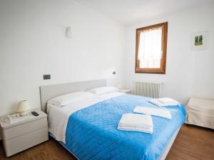 バルチスにあるApartment Albergo Diffuso - Cjasa de Pagnocca-1 by Interhomeの白いベッドルーム(青いベッド1台、窓付)