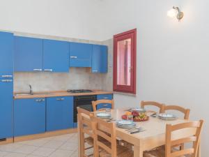 コスタ・レイにあるHoliday Home Case Greche Basse - REI235 by Interhomeのキッチン(青いキャビネット、テーブル、椅子付)