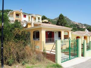 una casa gialla con una recinzione verde davanti di Holiday Home Case Greche Basse - REI235 by Interhome a Costa Rei